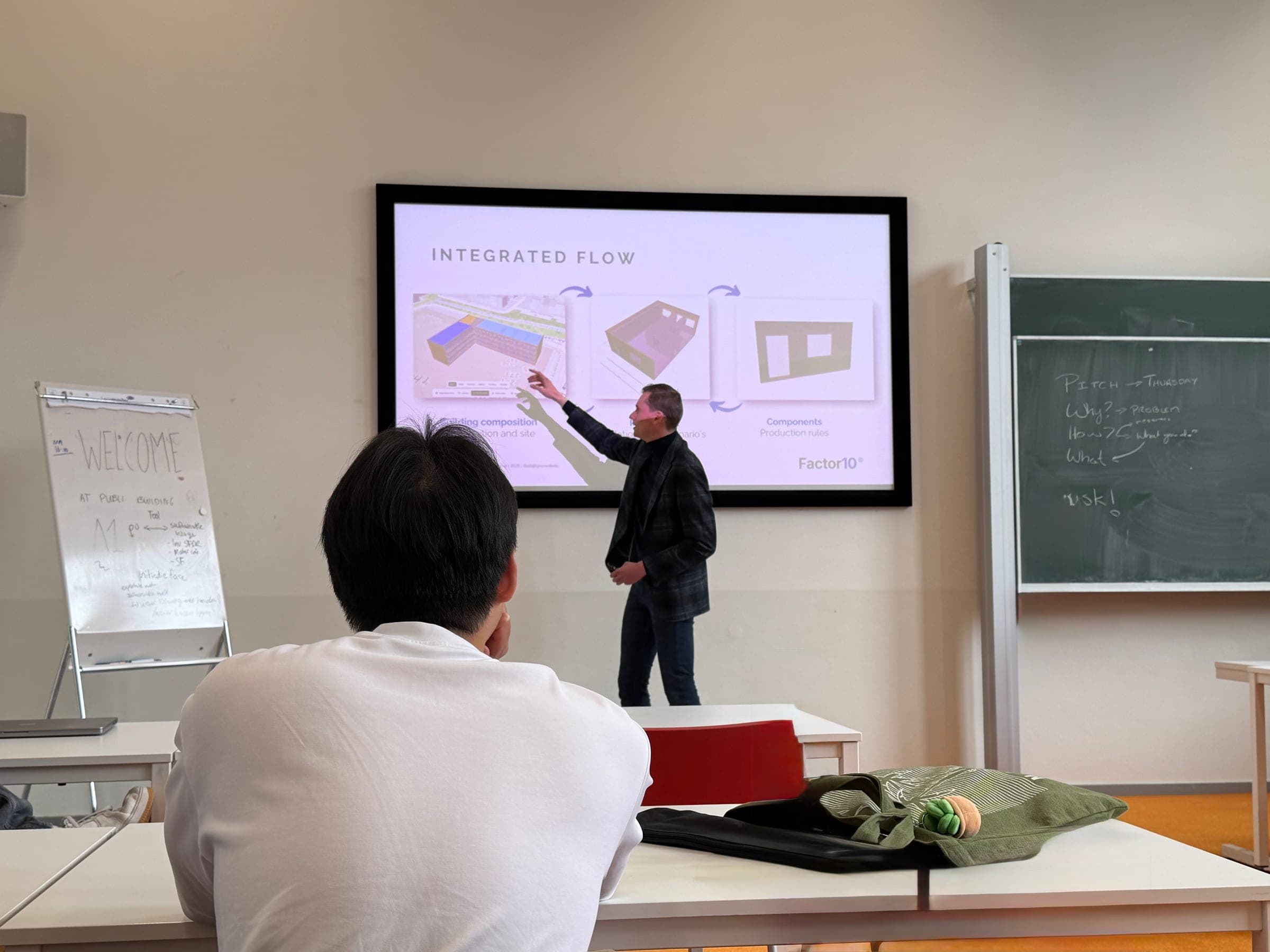 Chris Aerts licht in een collegezaal de geïntegreerde werkwijze van Factor10 toe, van gebouwopzet tot component