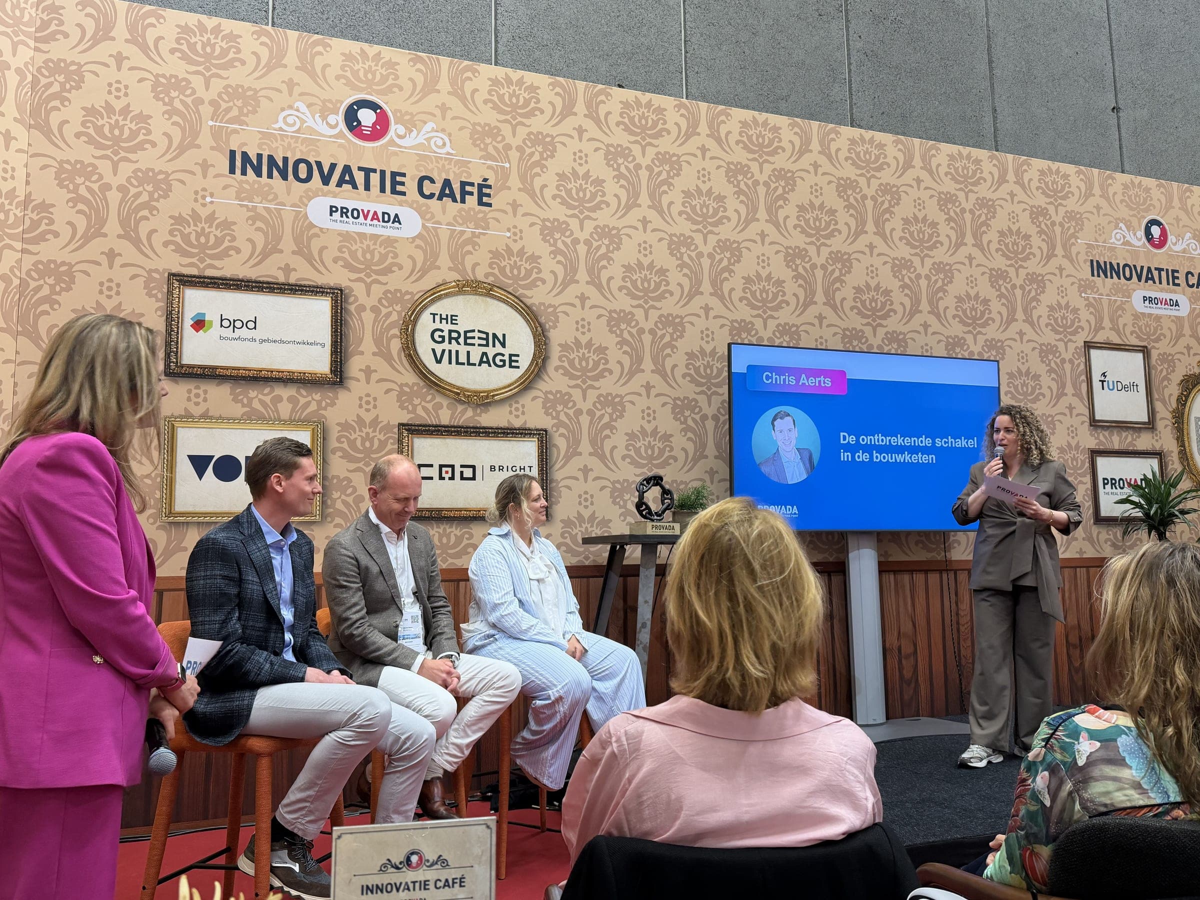 Chris Aerts op het podium van het Innovatie Café op de PROVADA, met op het scherm zijn pitch 'De ontbrekende schakel in de bouwketen'